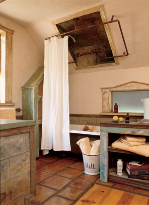 The tub surround is made of hammered metal, with copper tubing supporting the shower curtain. “And,” John laughs, “I purposely did the worst soldering job I could possibly do, to get the right look.” Because the room was originally an attic, the ceiling was too short for a shower. John cut a hole in the roof and lined it with hammered metal. While their only purpose is to hold the shower curtain, the copper pipes add the final touch.